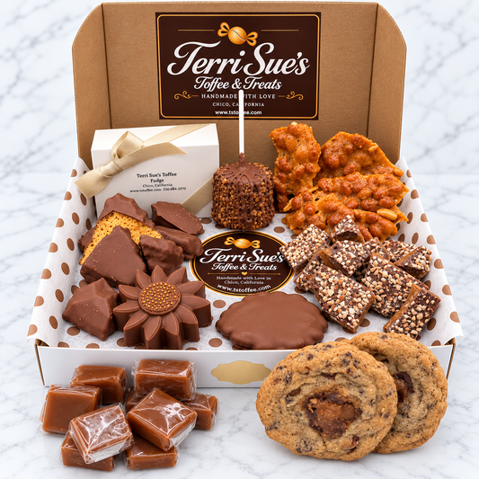 A gift box of Terri Sue's Coffee & Treats filled with assorted chocolates, cookies, and candy, displayed on a white marble surface. The open box contains various chocolate-dipped items, caramel-fried snacks, sprinkled chocolate bars, wrapped candies, and two chocolate chip cookies.