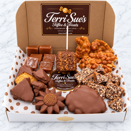 An open gift box of Terri Sue's Coffee & Treats filled with assorted chocolates, nuts, and caramel-topped treats on a white marble surface. The box is brown with polka-dot lining and a branded insert card.